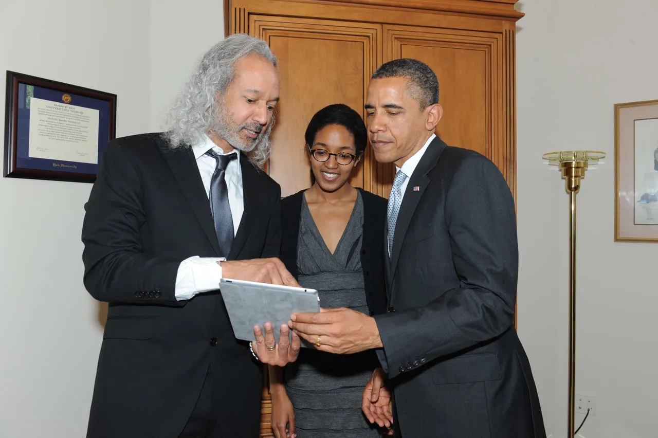 Barack Obama and two other people looking at the tablet